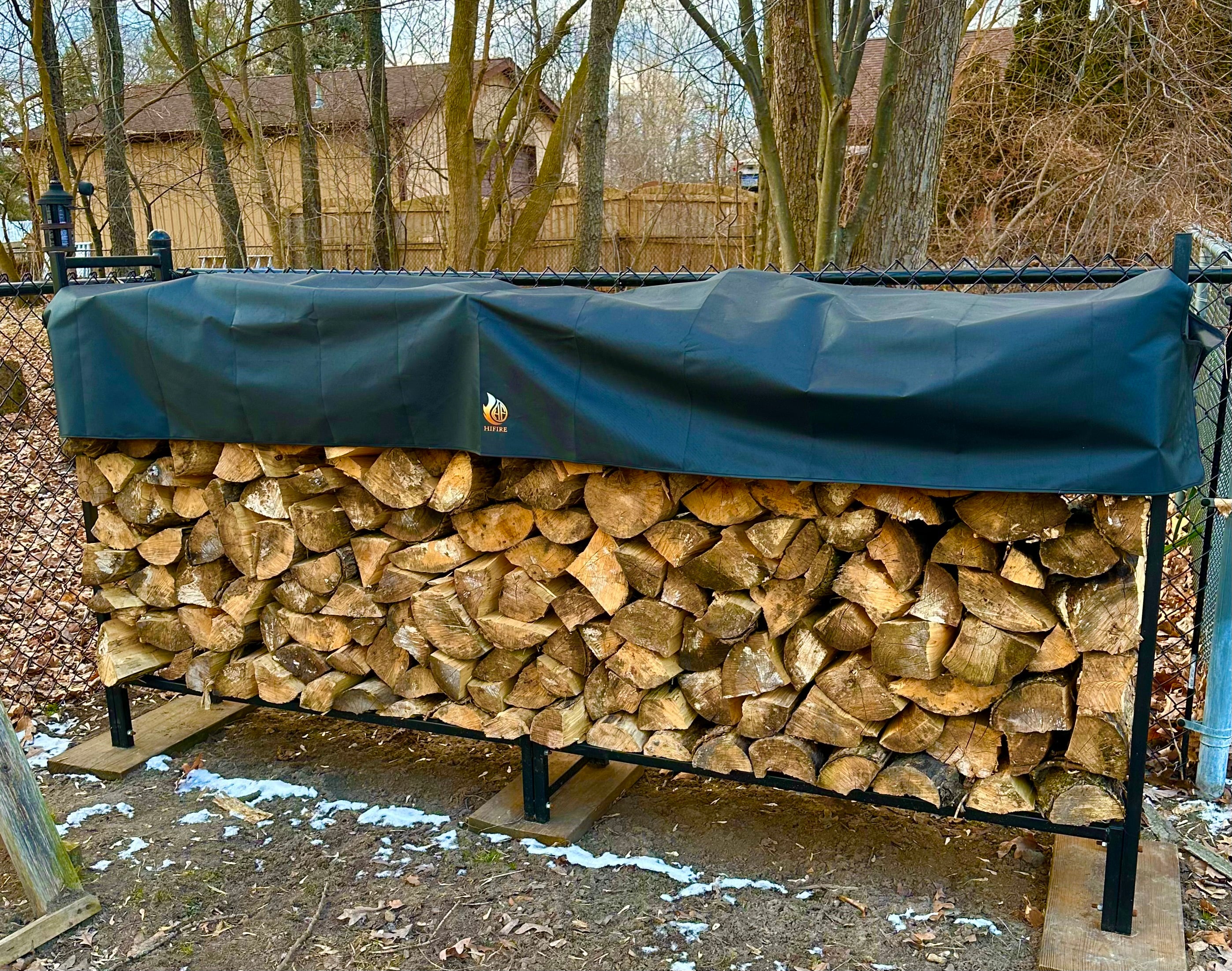 Stack of firewood on a rack with a black cover outdoors