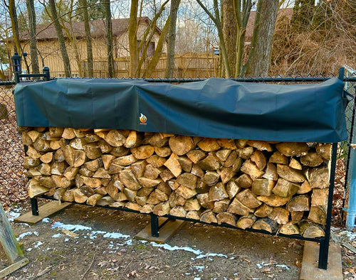 Stack of firewood on a rack with a black cover outdoors